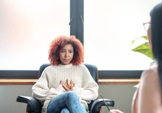 Talking to psychoanalyst. Young woman wearing jeans sitting near window and talking to psychoanalyst